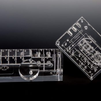 Precision Machined Acrylic Manifold Next to a Clear Diffusion Bonded Acrylic Fluidic Manifold