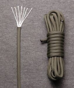 Image of nylon parachute cord. A strand on the left is snipped at the end and the fibers within are splayed out for viewing. On the right is a full rope of nylon, wrapped neatly for storage. 